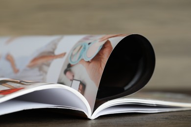 Photo of One open magazine on wooden table, closeup