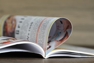 Photo of One open magazine on wooden table, closeup