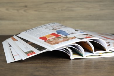 Photo of Different open magazines on wooden table, closeup