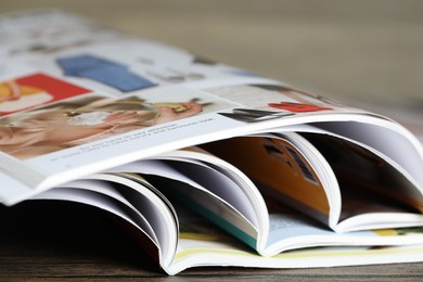 Photo of Different open magazines on wooden table, closeup