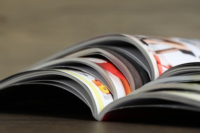 Photo of Different open magazines on wooden table, closeup