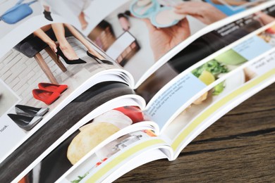Photo of Different open magazines on wooden table, above view