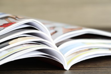 Photo of Different open magazines on wooden table, closeup
