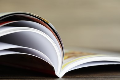 Photo of One open magazine on wooden table, closeup