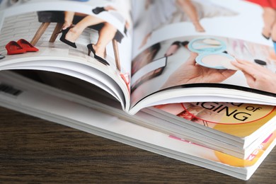Photo of Stack of different magazines on wooden table, closeup