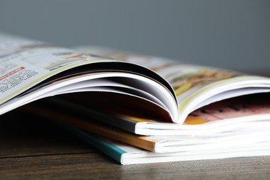 Photo of Stack of different magazines on wooden table, closeup