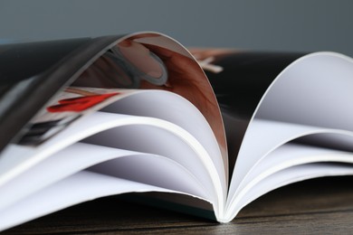 Photo of One open magazine on wooden table, closeup