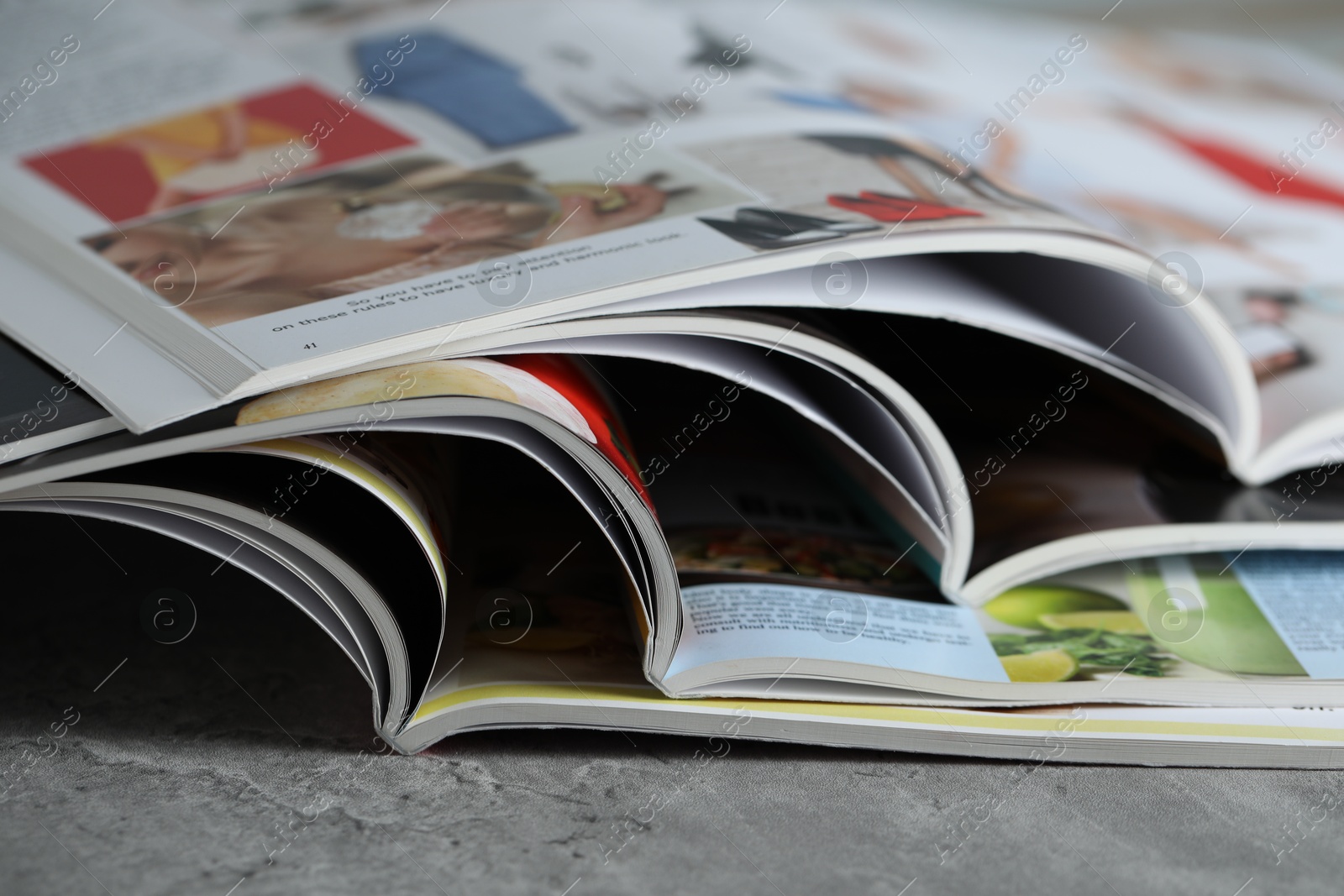 Different open magazines on grey table, closeup Photo of Different open magazines on grey table, closeup