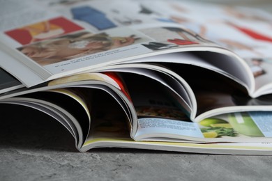 Photo of Different open magazines on grey table, closeup