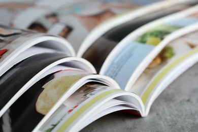 Photo of Different open magazines on grey table, closeup