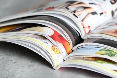 Photo of Different open magazines on grey table, closeup