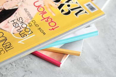 Photo of Stack of different magazines on grey table, above view