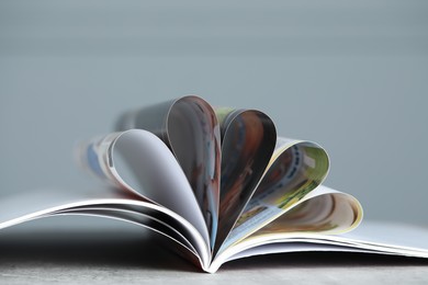 Photo of One open magazine on grey table, closeup