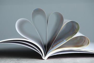 Photo of One open magazine on grey table, closeup