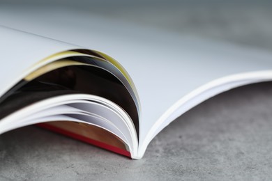Photo of One open magazine on grey table, closeup