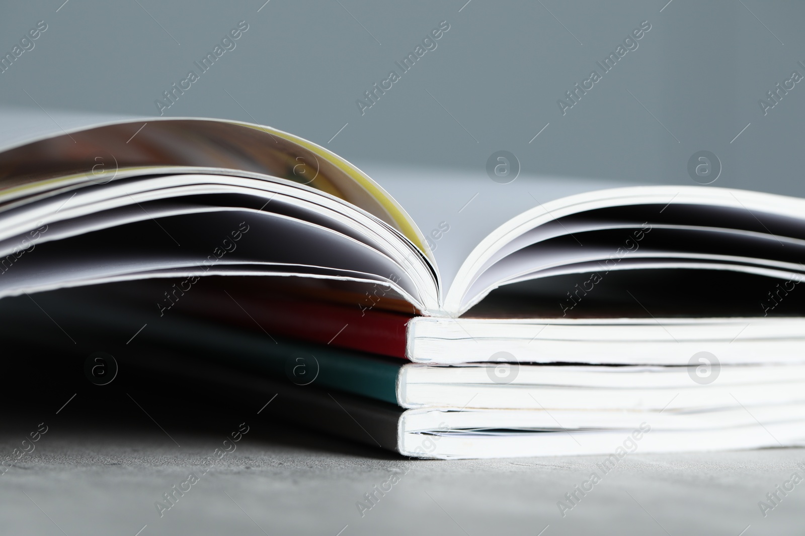 Stack of different magazines on grey table, closeup Photo of Stack of different magazines on grey table, closeup