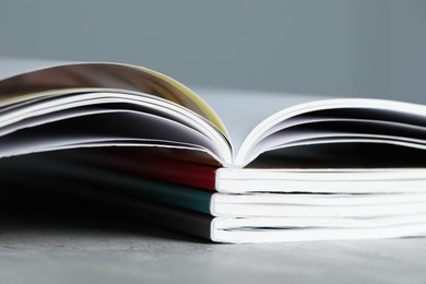 Photo of Stack of different magazines on grey table, closeup