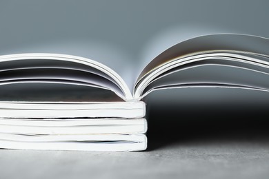 Photo of Stack of different magazines on grey table, closeup