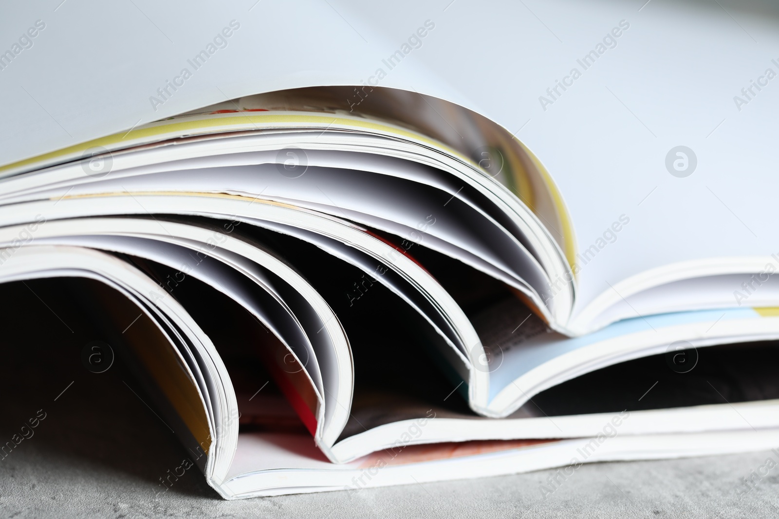 Different open magazines on grey table, closeup Photo of Different open magazines on grey table, closeup