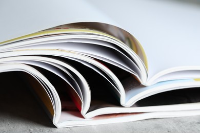 Photo of Different open magazines on grey table, closeup