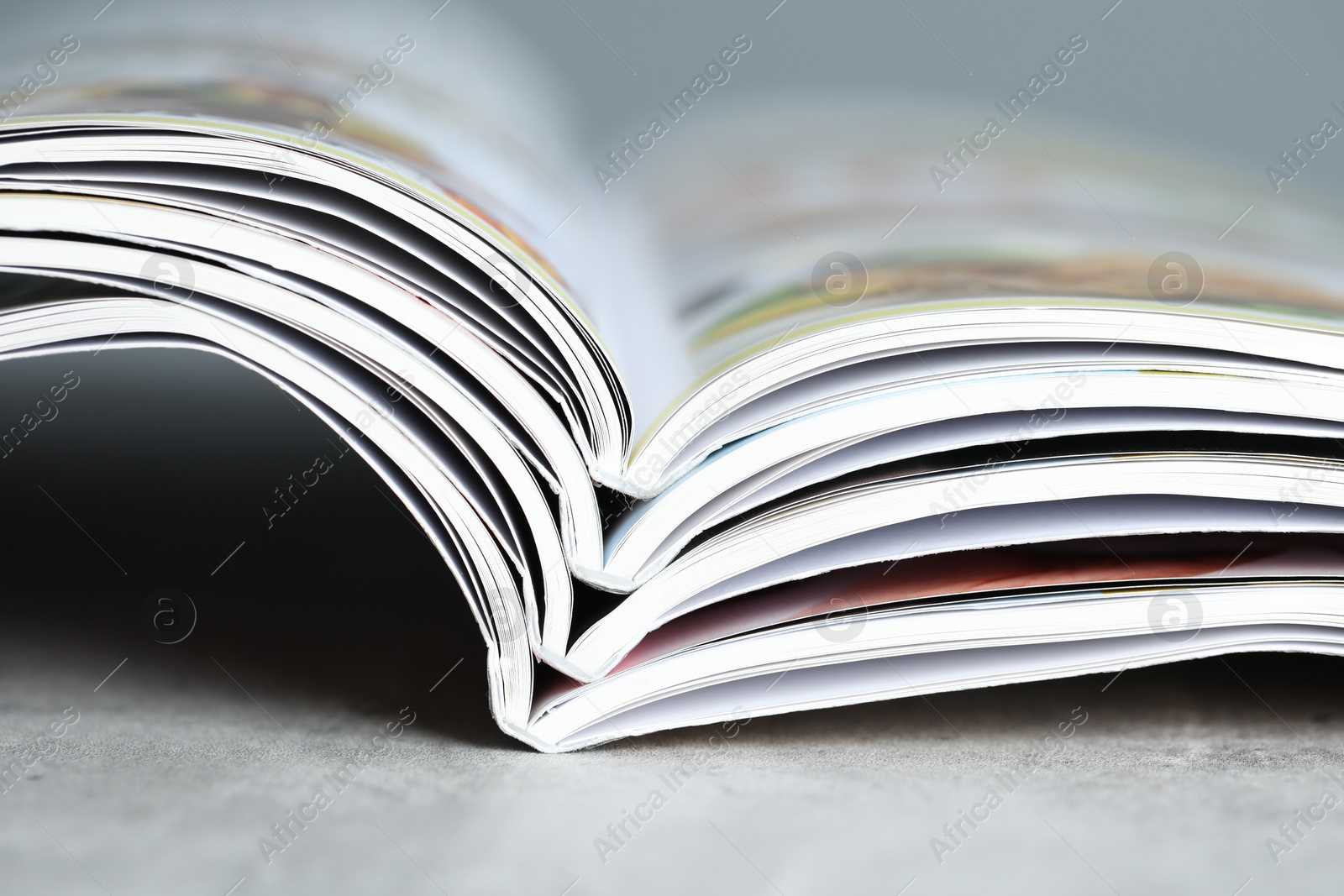 Different open magazines on grey table, closeup Photo of Different open magazines on grey table, closeup
