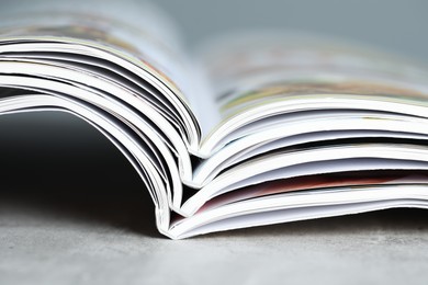 Photo of Different open magazines on grey table, closeup