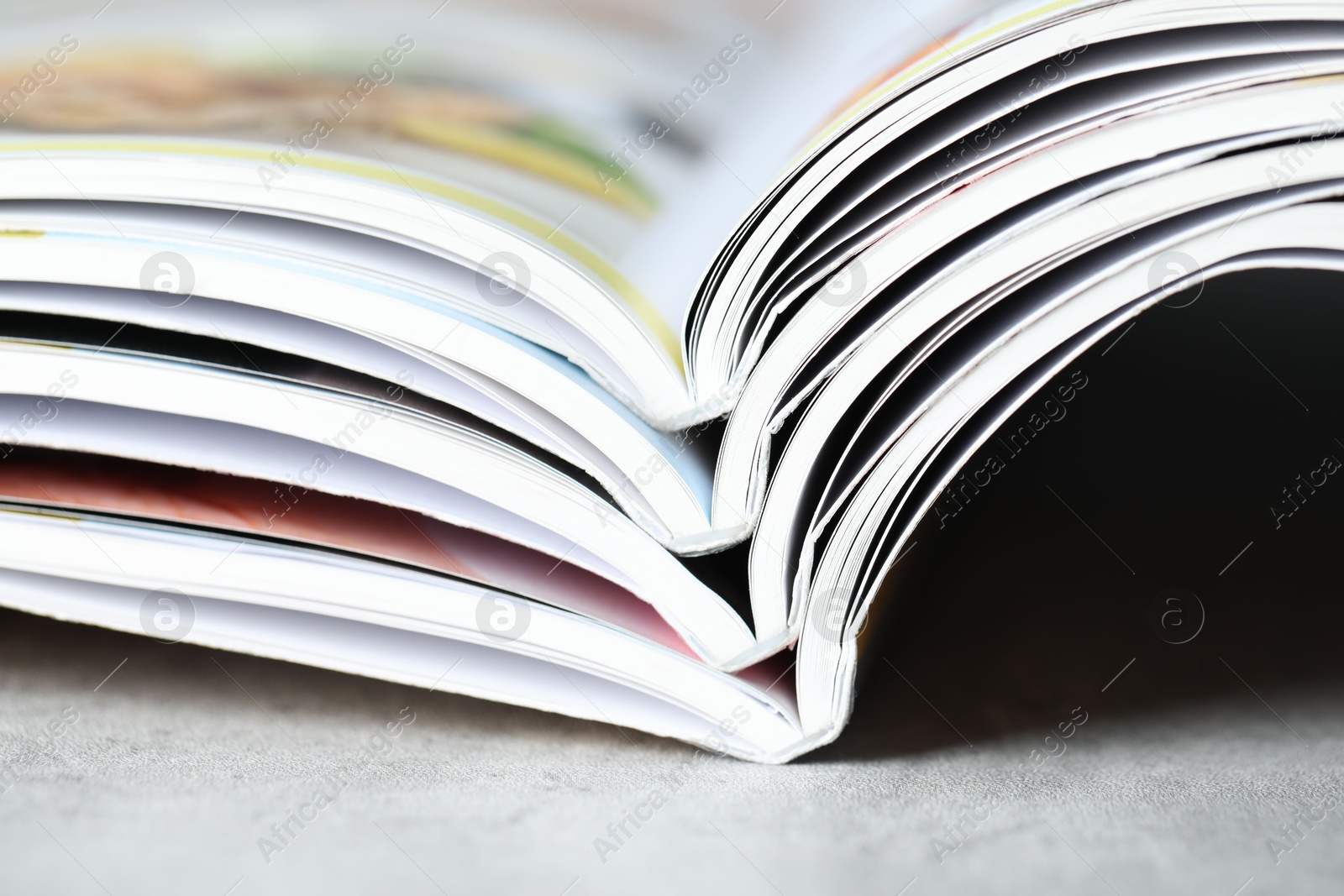 Different open magazines on grey table, closeup Photo of Different open magazines on grey table, closeup
