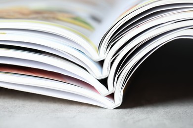 Photo of Different open magazines on grey table, closeup