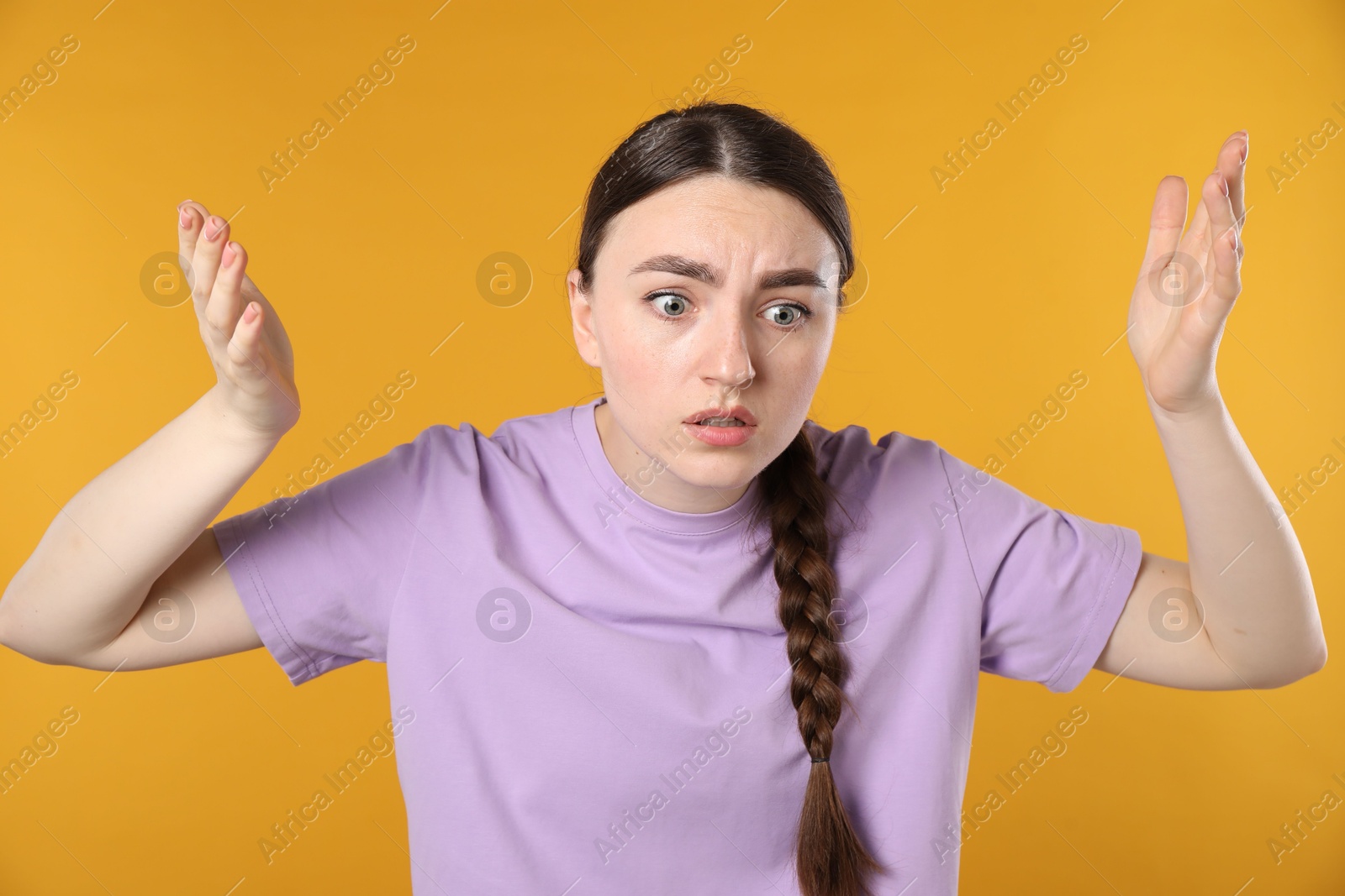 Photo of Portrait of confused woman on orange background