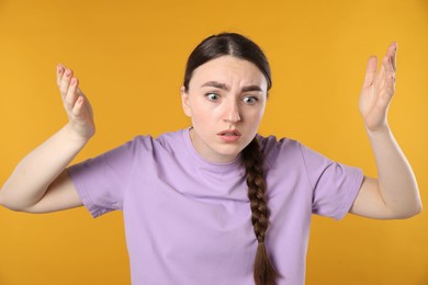 Photo of Portrait of confused woman on orange background