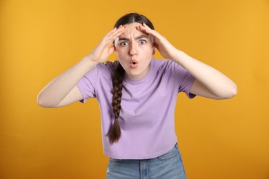 Photo of Portrait of shocked woman on orange background