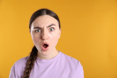 Photo of Portrait of shocked woman on orange background, space for text