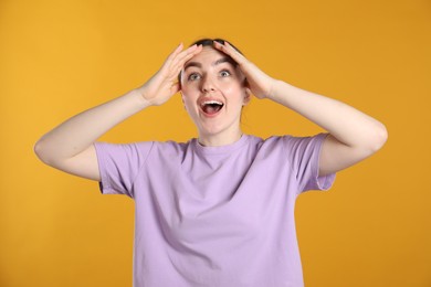 Photo of Portrait of surprised woman on orange background