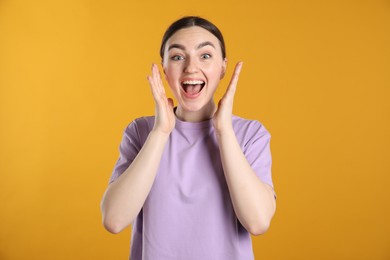 Photo of Portrait of surprised woman on orange background