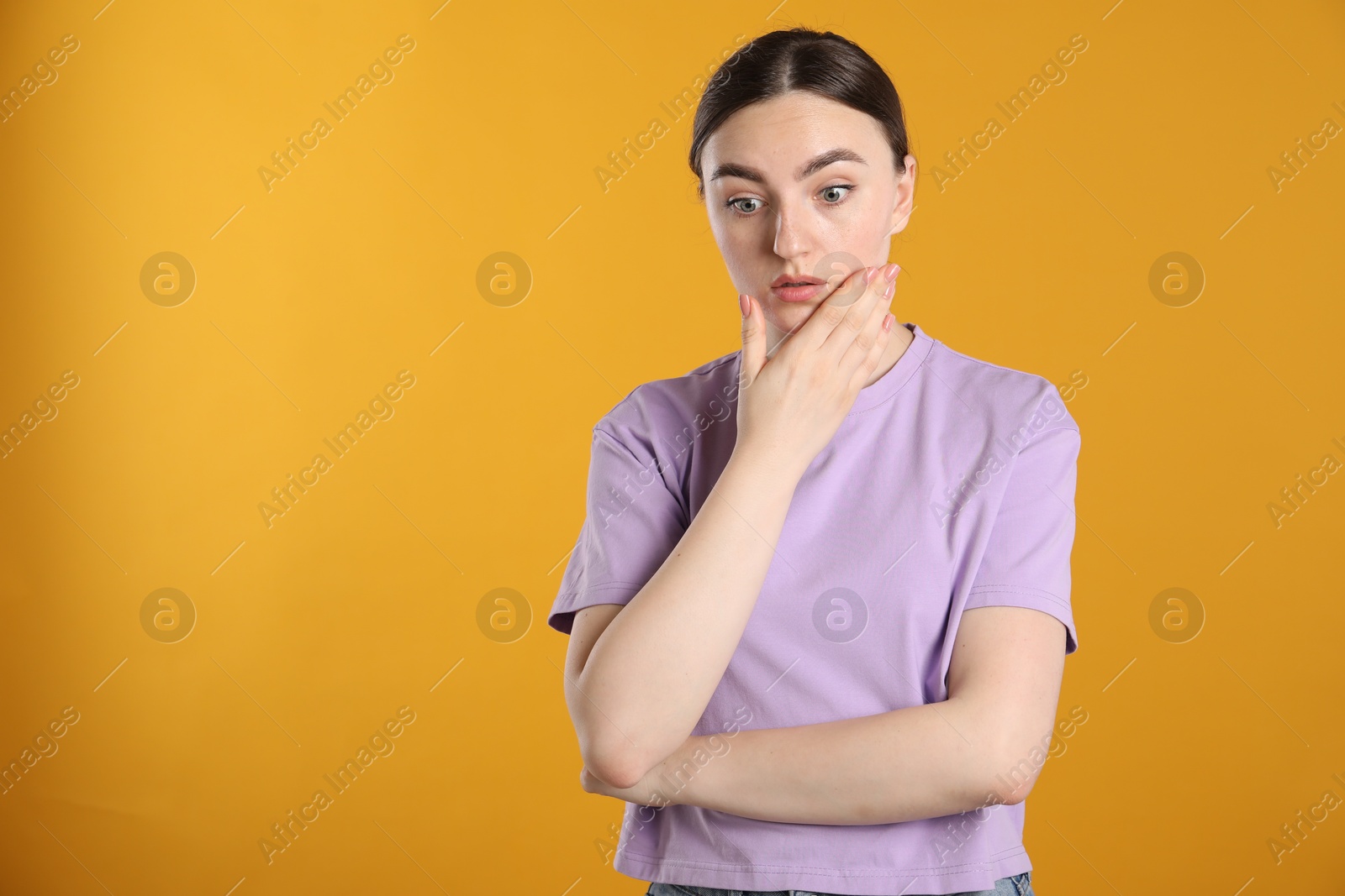 Portrait of confused woman on orange background, space for text Photo of Portrait of confused woman on orange background, space for text