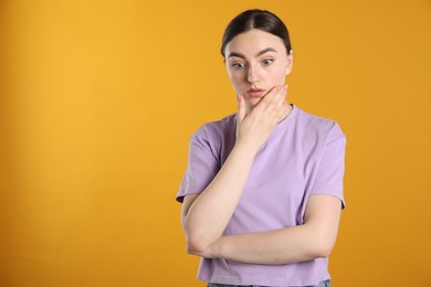 Photo of Portrait of confused woman on orange background, space for text