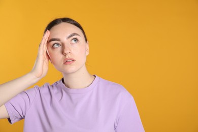 Photo of Portrait of confused woman on orange background, space for text