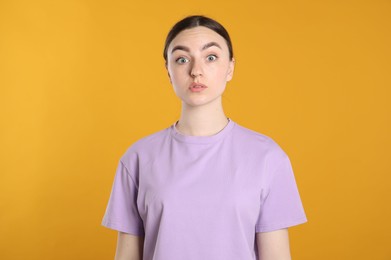 Photo of Portrait of confused woman on orange background