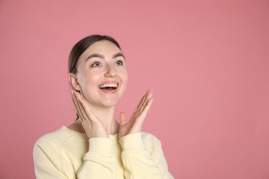 Photo of Portrait of surprised woman on pink background, space for text