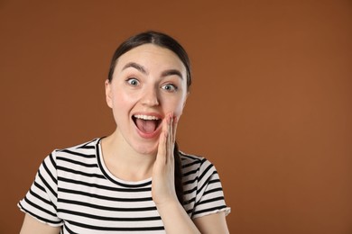Photo of Portrait of surprised woman on brown background, space for text