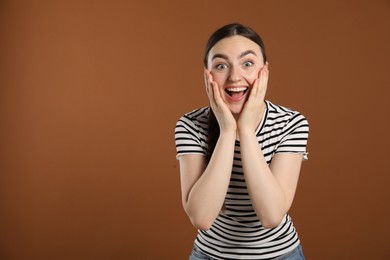 Photo of Portrait of surprised woman on brown background, space for text