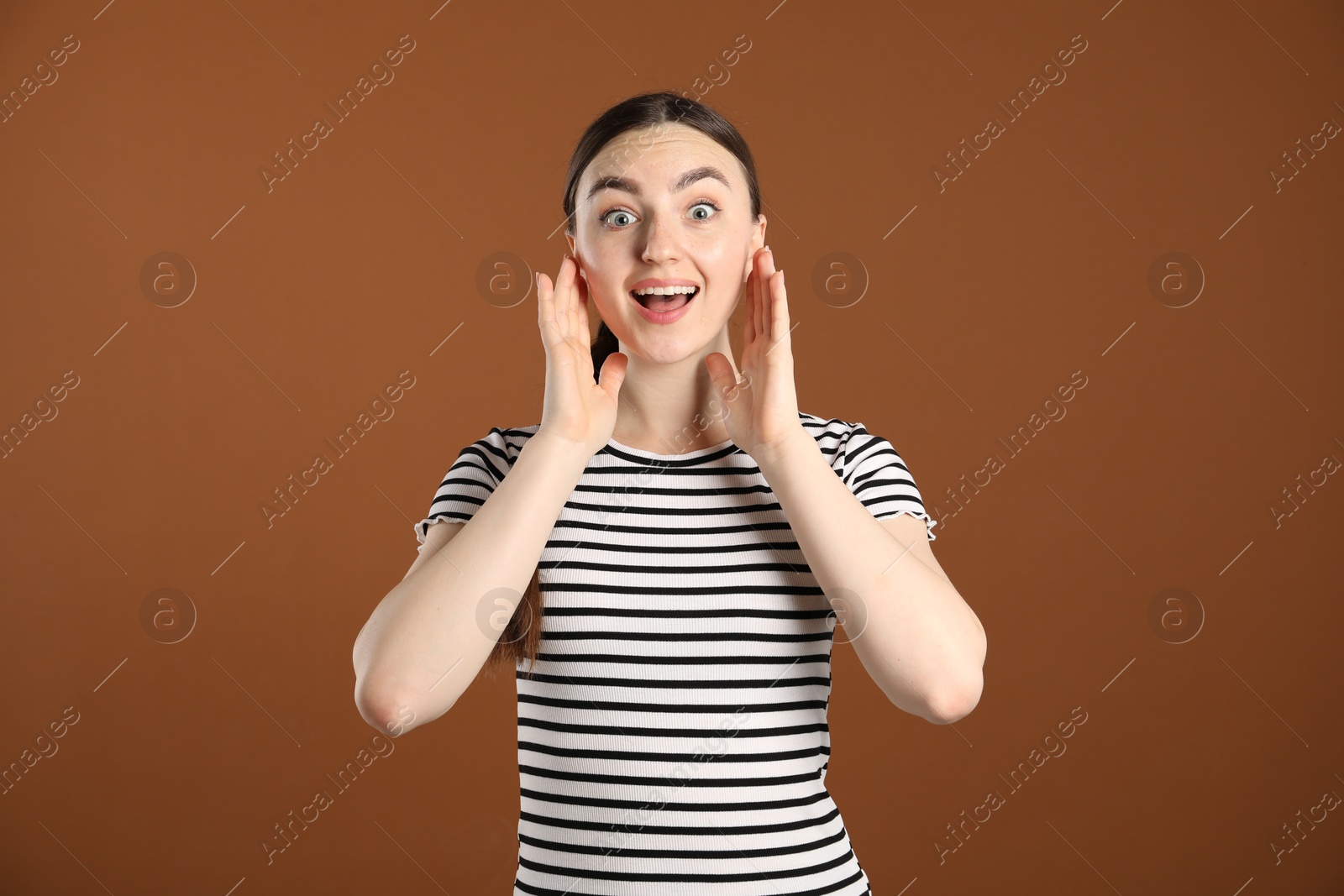 Portrait of surprised woman on brown background Photo of Portrait of surprised woman on brown background