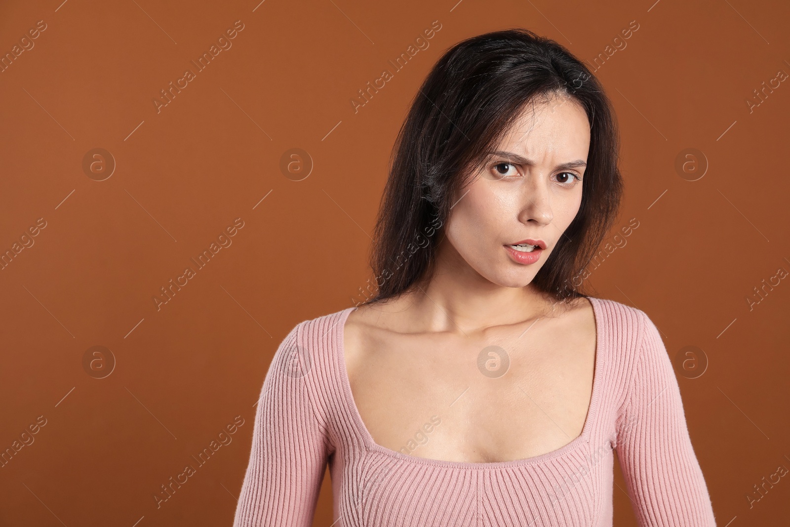 Portrait of confused woman on brown background, space for text Photo of Portrait of confused woman on brown background, space for text