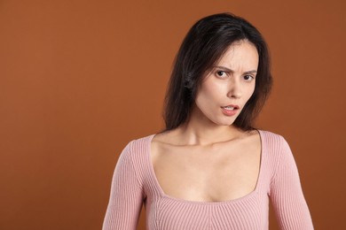 Photo of Portrait of confused woman on brown background, space for text