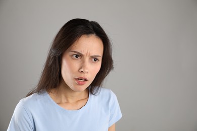 Photo of Portrait of shocked woman on grey background, space for text