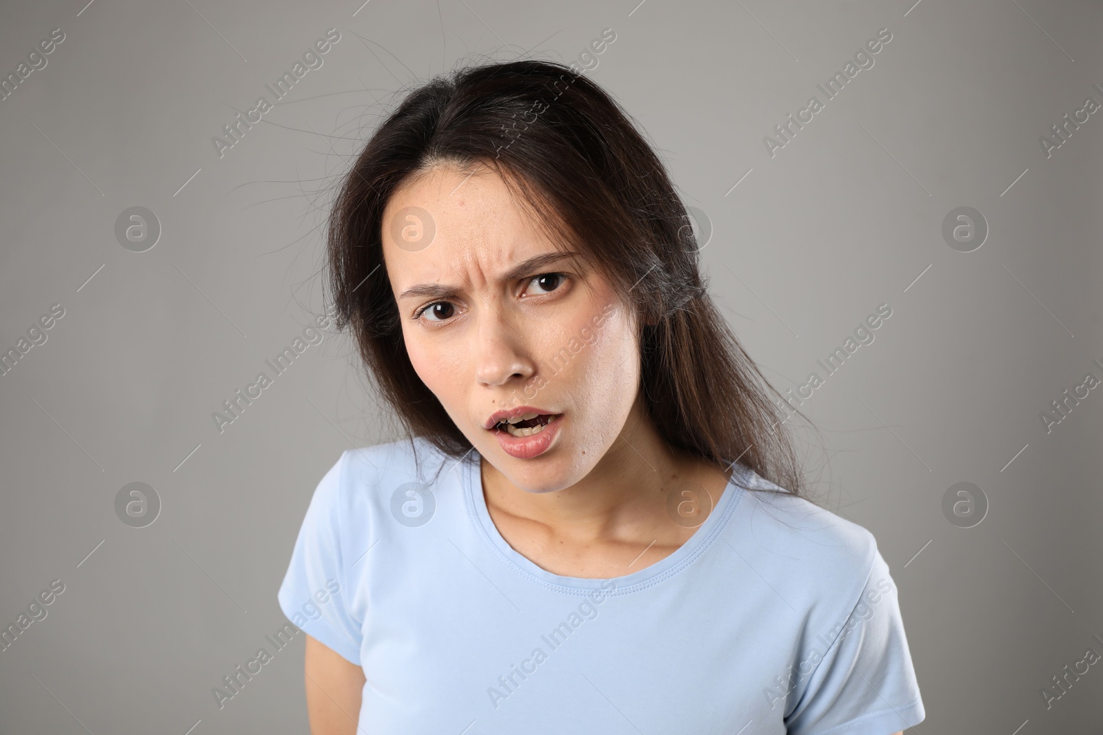Portrait of confused woman on grey background Photo of Portrait of confused woman on grey background