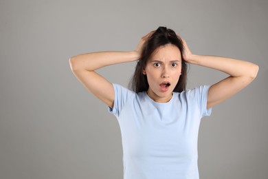 Photo of Portrait of shocked woman on grey background, space for text