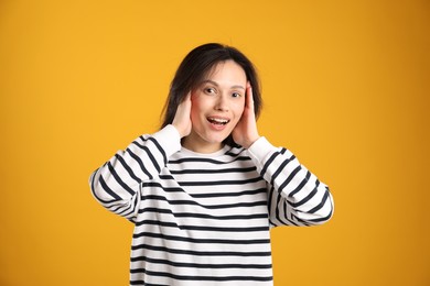 Photo of Portrait of surprised woman on orange background
