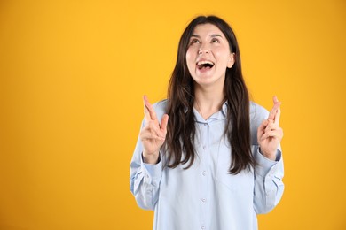 Photo of Surprised woman pointing at something on orange background, space for text