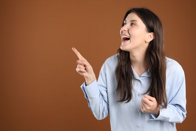 Photo of Portrait of surprised woman on brown background, space for text